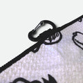Close-up of a black carabiner attached to a waffle golf towel on a light gray background.