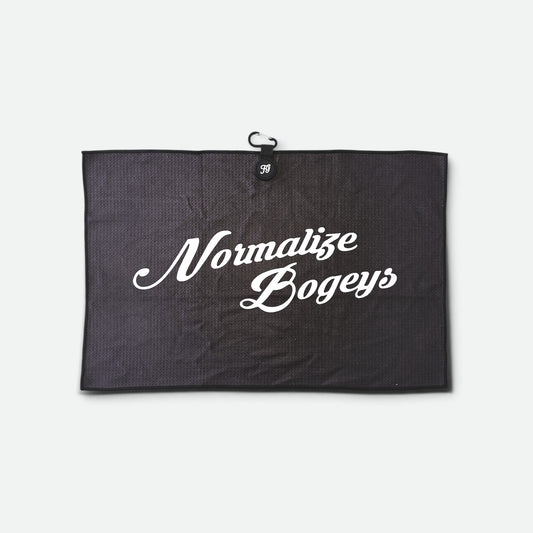 A black textured waffle golf towel with a small black hanging loop at the top and the phrase 'Normalize Bogeys' printed in white script across the centre, shown against a light grey background.