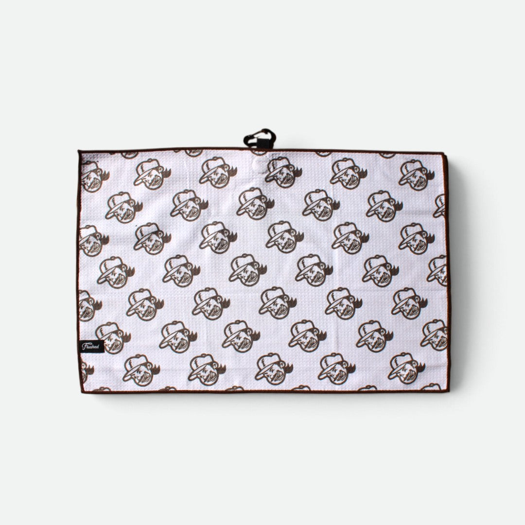 A waffle golf towel with a white background, brown border, and an all-over repeating flushed golf mascot pattern with a black metal clip is attached at the top.
