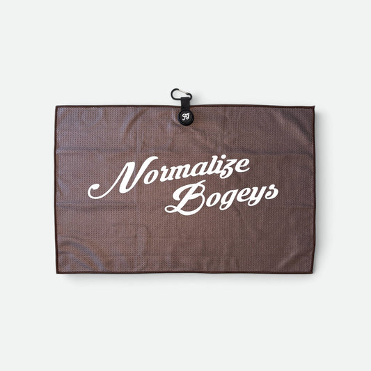 A brown textured waffle golf towel with white script text reading 'Normalize Bogeys' and a small black hanging loop at the top, shown on a light grey background.